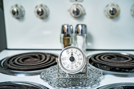 Close-up of a classic analog kitchen timer on a vintage gas stove, perfect for cooking themes.