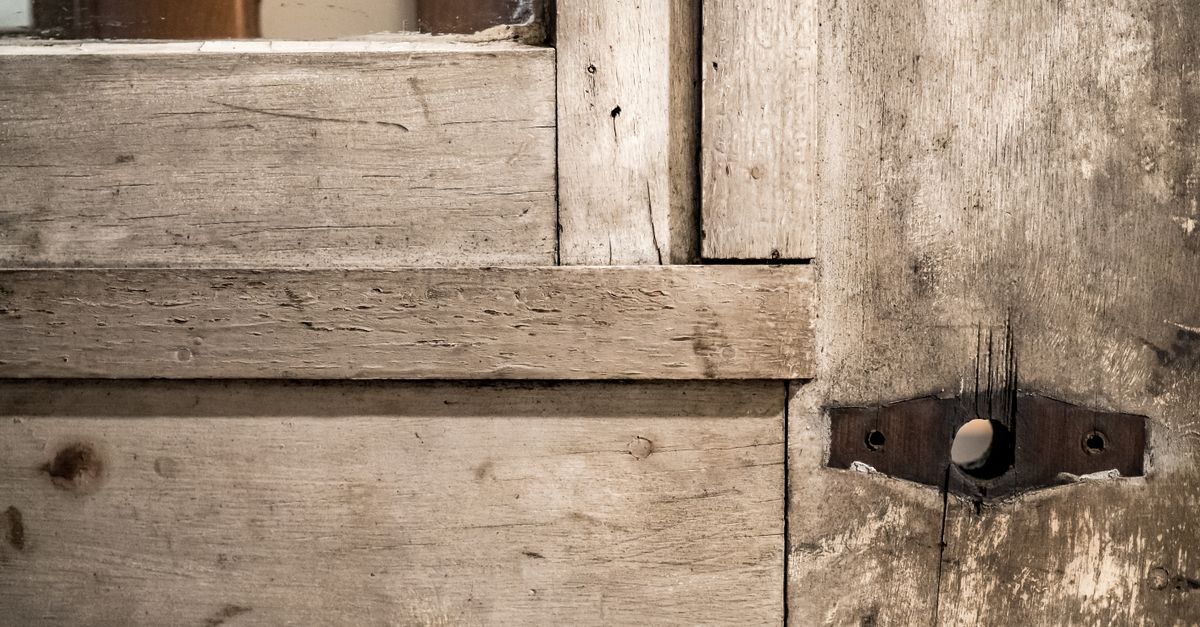 Damaged hinge screws on a wooden door.