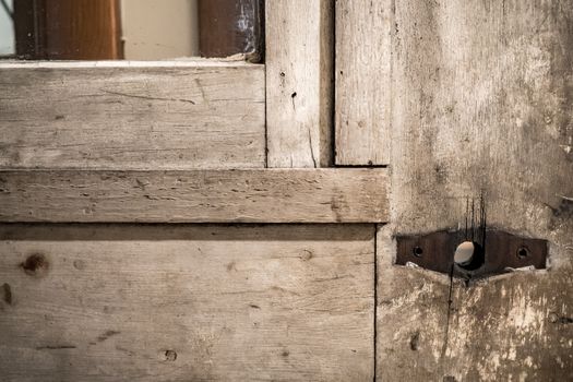 Close-up of an old, weathered wooden door with rusty hinges, showcasing vintage charm.