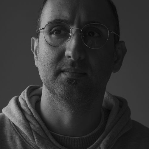Free Black and white portrait of a man with eyeglasses in a hoodie, exuding a contemplative mood. Stock Photo