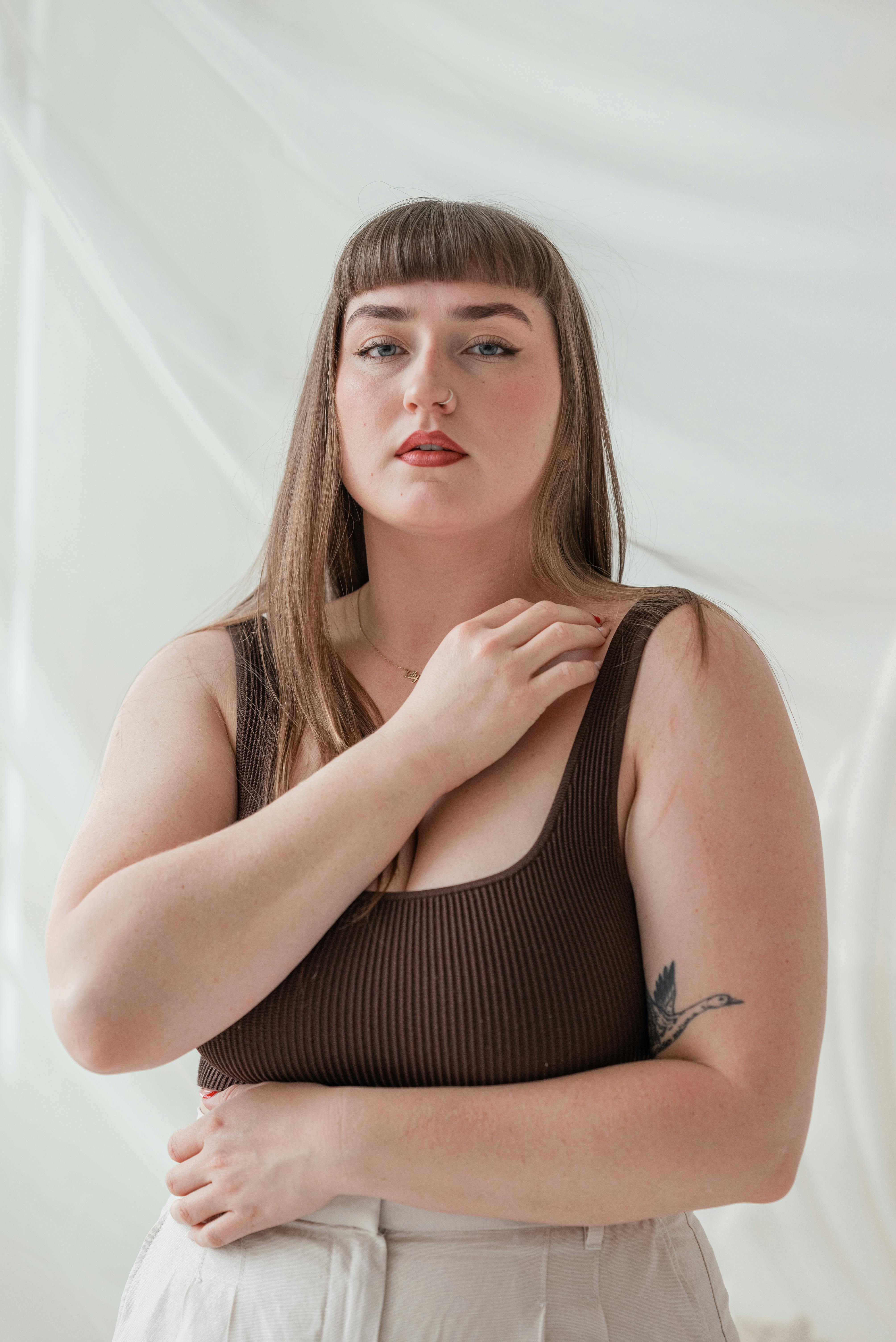 A stylish portrait of a woman with long brown hair against a soft, white background.