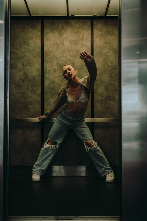 Woman in Elevator wearing Bra an Ripped Jeans 