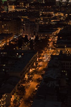 A breathtaking vertical shot of a cityscape at night, showcasing glowing streets and urban life.