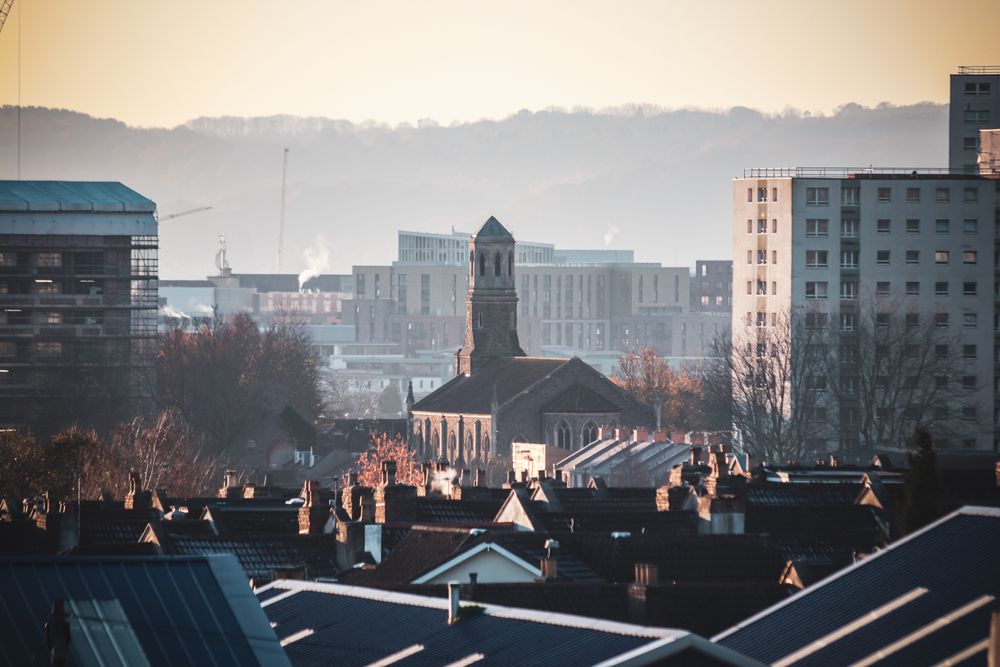 Urban view of Bristol featuring St Luke's Church amidst city buildings during a serene sunset.