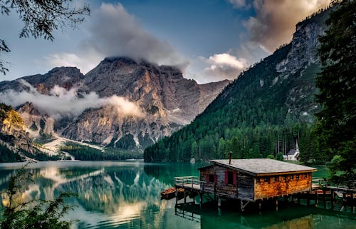 Mirror Lake Reflecting Wooden House in Middle of Lake Overlooking Mountain Ranges