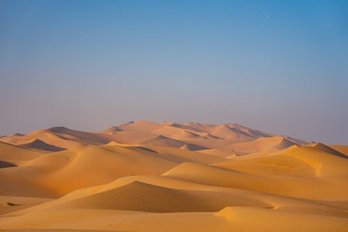 Free A stunning view of vast sand dunes beneath a vibrant blue sky, capturing the essence of desert tranquility. Stock Photo