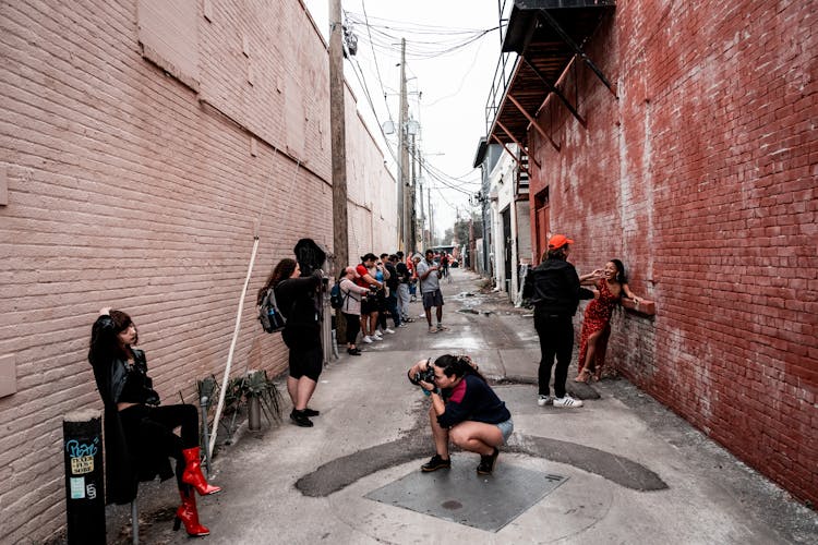 People On The Narrow Street Between Brick Buildings