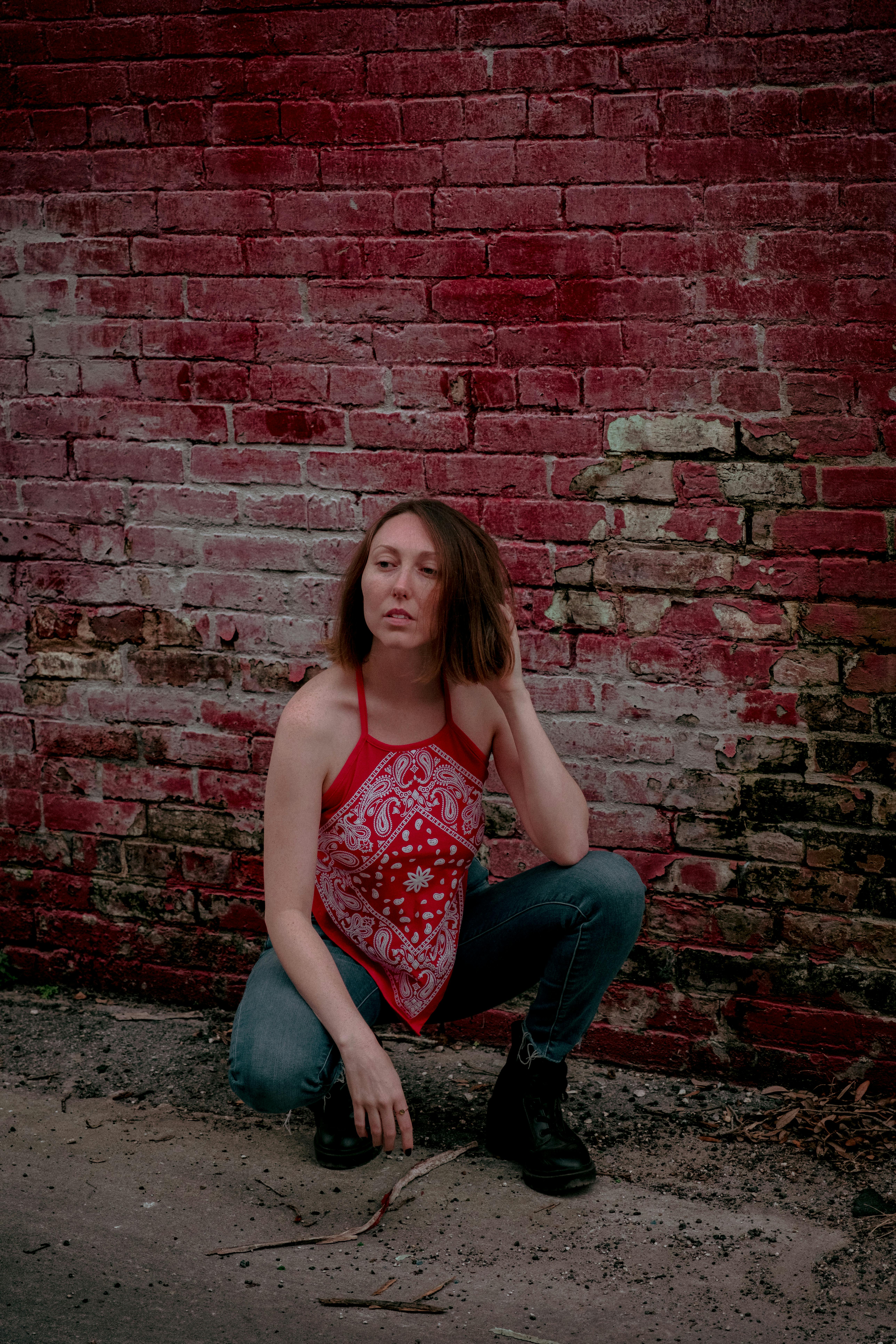 a woman in jeans and a red tank top crouches down