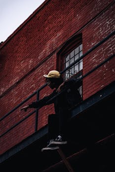 Moody urban portrait of a person sitting on a fire escape, highlighting city vibes.