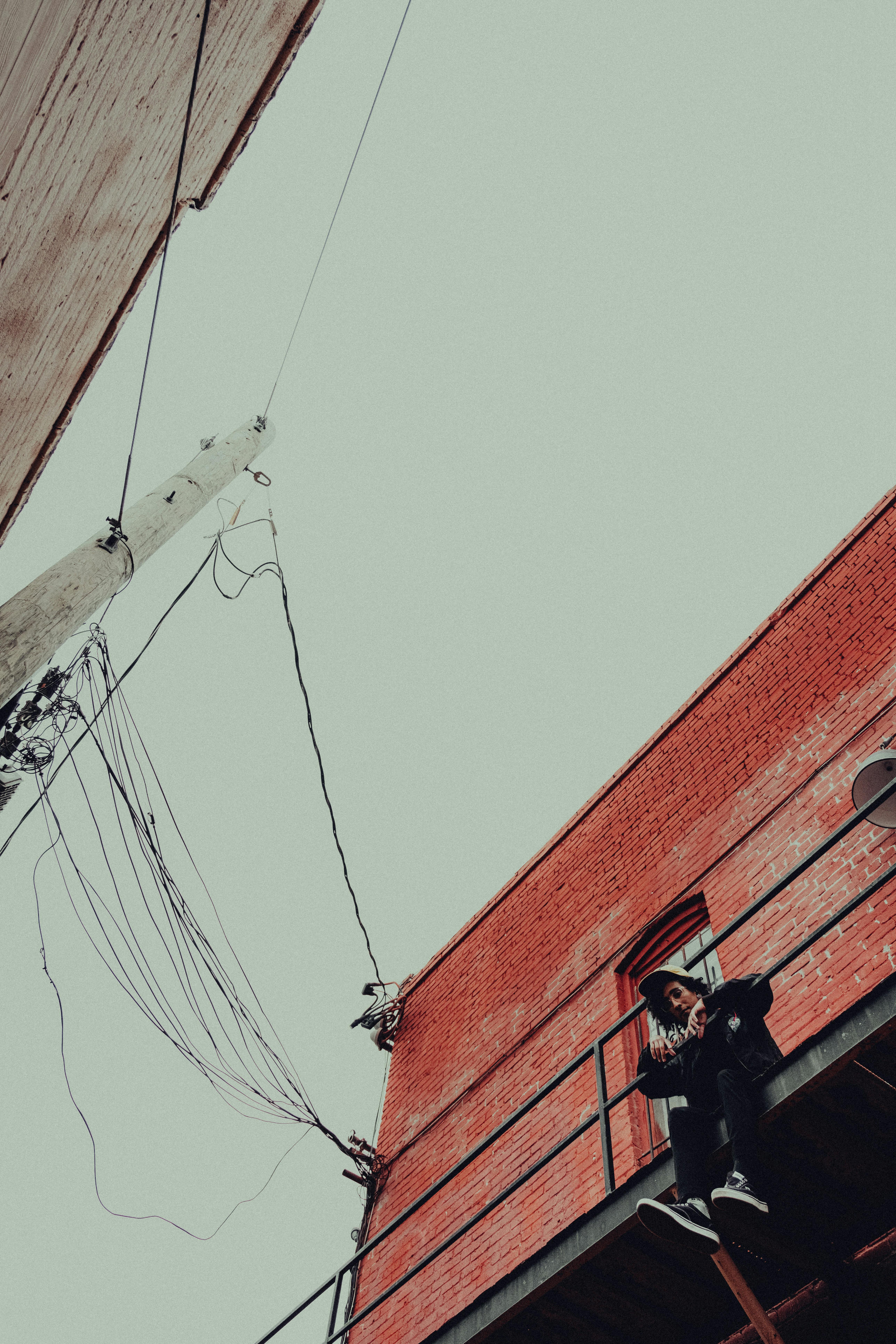 a man is standing on a ledge next to a building