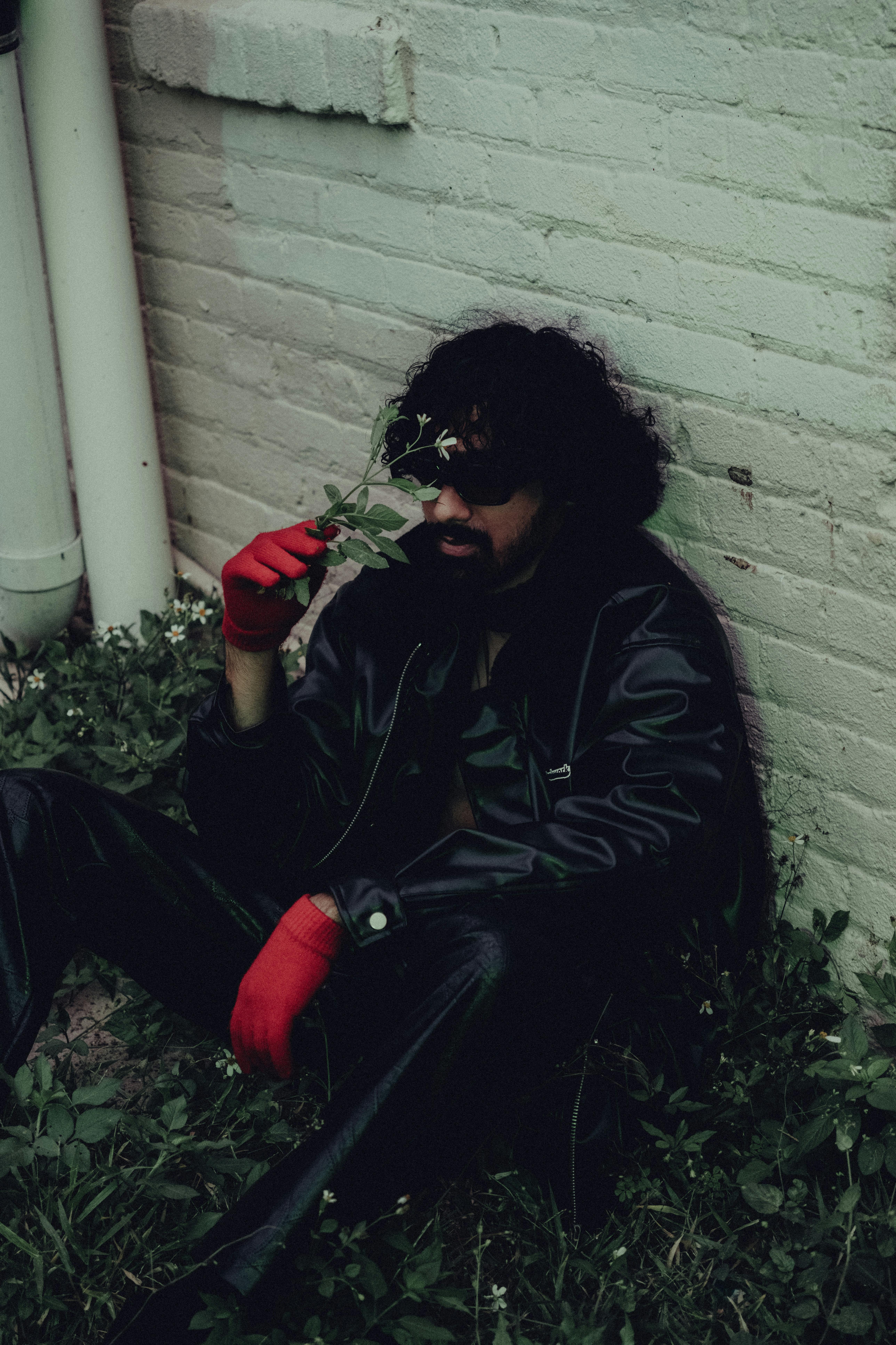 a man in red gloves and leather jacket sitting on the ground