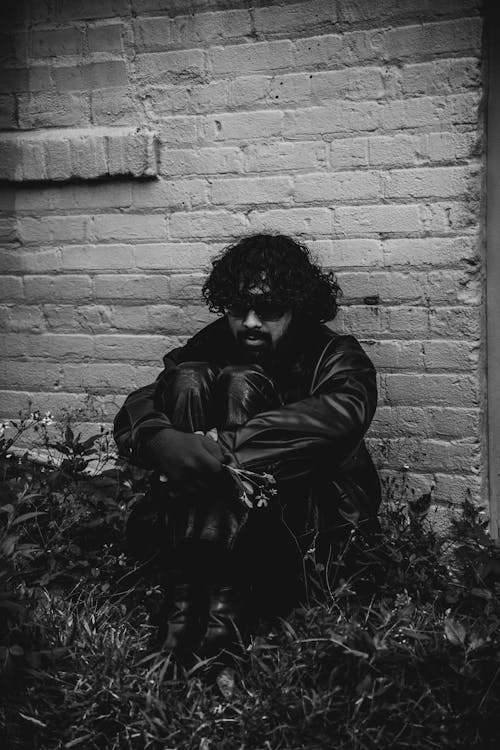 Monochrome Shot of a Depressed Man Beside the Concrete Wall