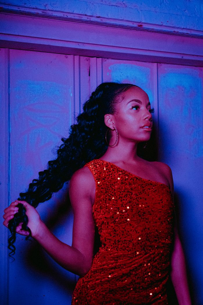 Guest in a red sequin one-shoulder gown beneath neon light