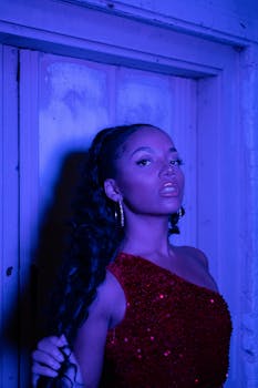 Elegant portrait of a woman in red dress illuminated by vivid blue neon light, indoor setting.