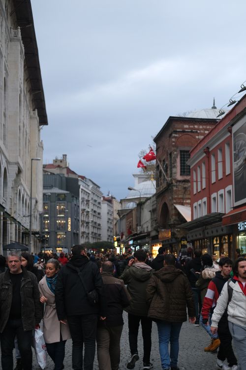 Free People walking through a busy shopping street under a cloudy sky. Stock Photo