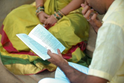 Free A man and woman in traditional attire reading a book outdoors, showcasing cultural heritage. Stock Photo