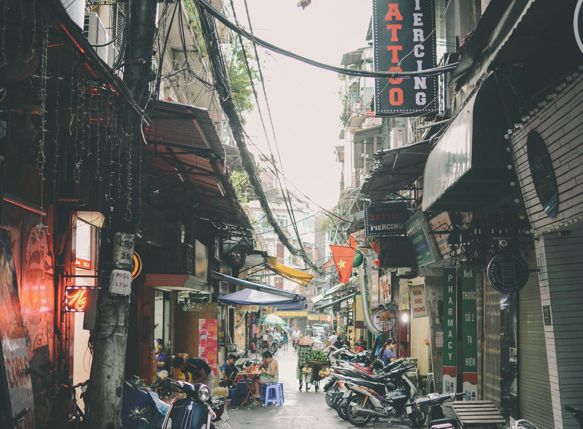 Vibrant urban atmosphere in a Hanoi alley with shops and motorbikes.