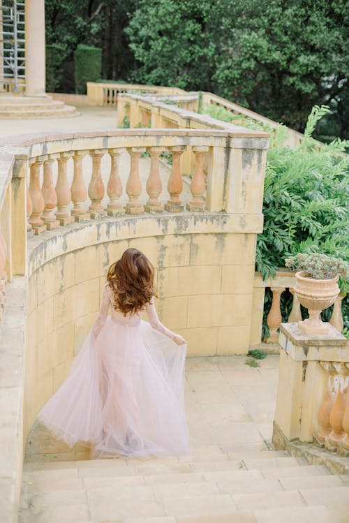 Photo of a Bride in a Tulle Wedding Dress Going Down the Stairs