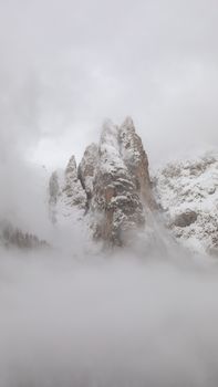 A breathtaking view of snow-capped peaks emerging from mist in Trentino-South Tyrol, Italy.