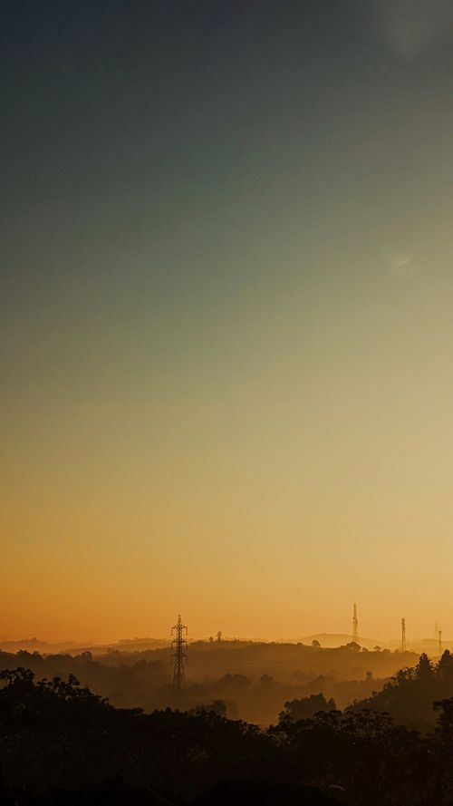 Free Tranquil landscape of Thiruvaniyoor hills at sunset, showcasing a vibrant yellow sky and rural countryside atmosphere. Stock Photo