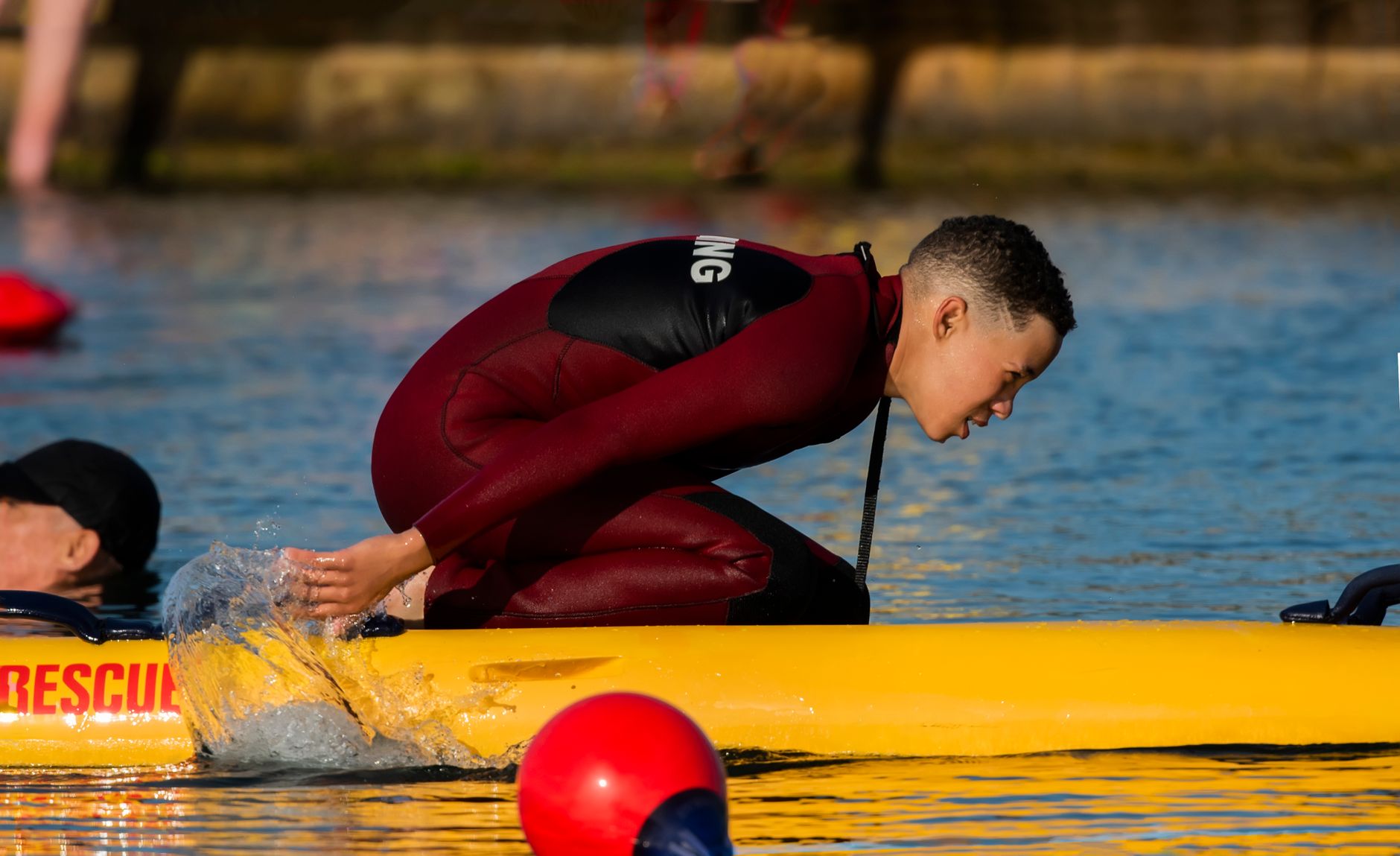 A lifeguard performing an open-water rescue demonstration, illustrating the high-stakes training that prepares junior guards for real emergencies.