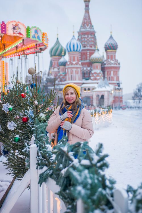 Free A woman bundled in winter clothes stands in snowy Moscow near St. Basil's Cathedral. Stock Photo