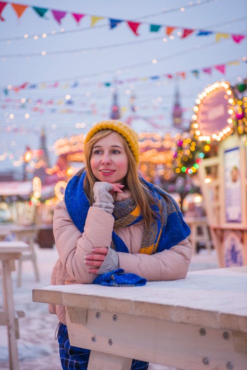 Free Cheerful woman in winter clothing enjoying a snowy festive market. Stock Photo