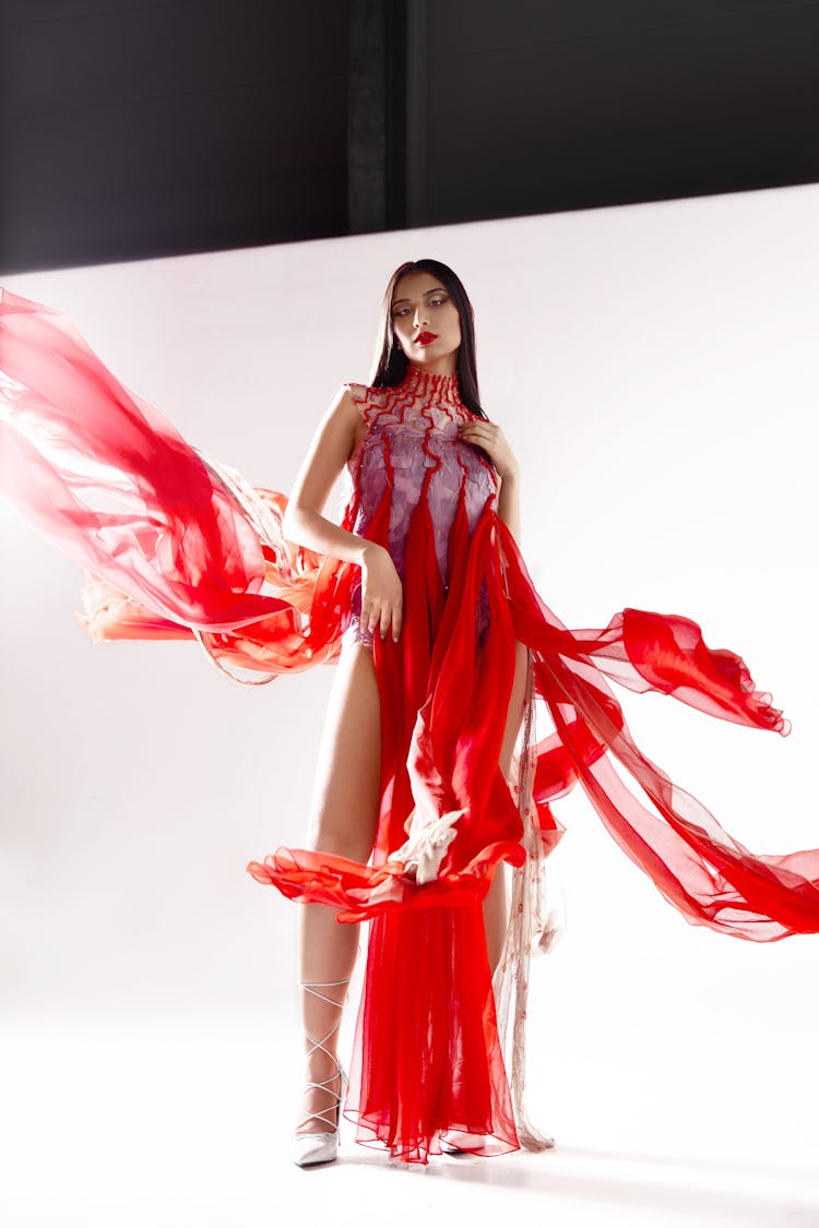 Woman In Red Fashion Dress In Studio