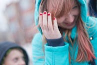 一位快乐的女子留着红指甲，在户外捏着头发微笑