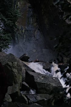 A stunning waterfall cascading over mossy rocks amidst lush greenery, creating a serene natural scene.