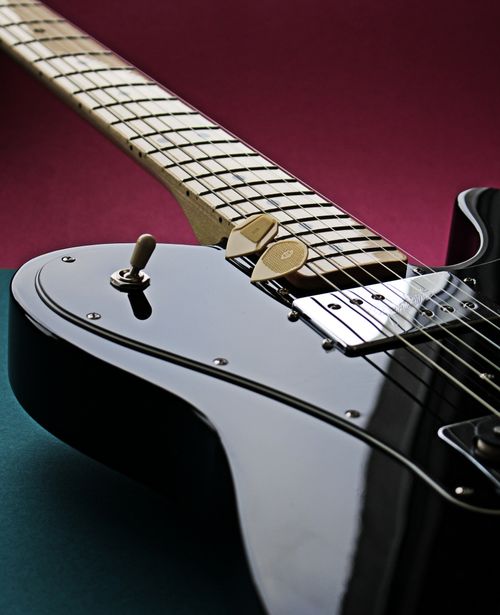Free Detailed shot of a glossy black electric guitar with guitar picks on a contrasting background. Stock Photo