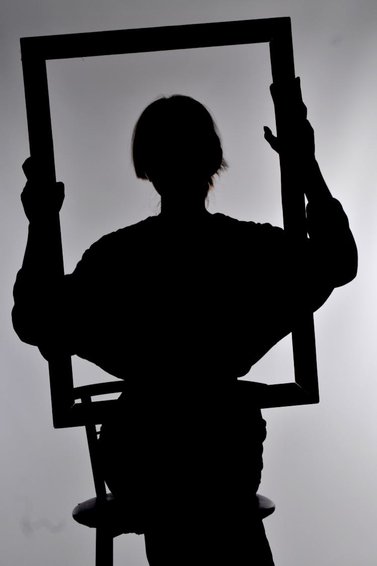 Silhouette Of A Woman Holding A Painting Frame