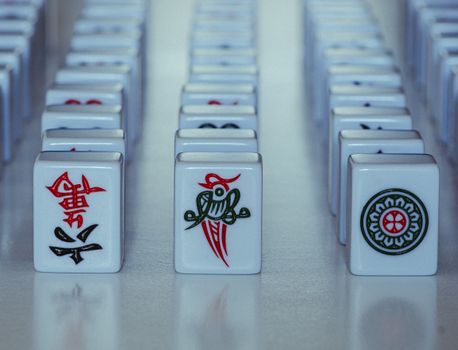 Detailed close-up of traditional Mahjong tiles lined up on a reflective surface.