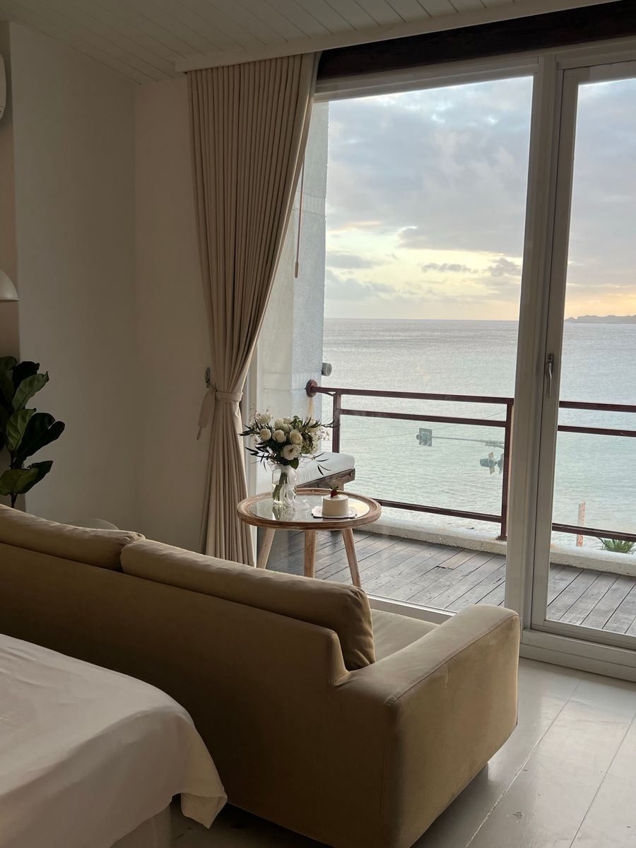 A suite sitting room with a soft sofa and a glass balcony door looking out to sea