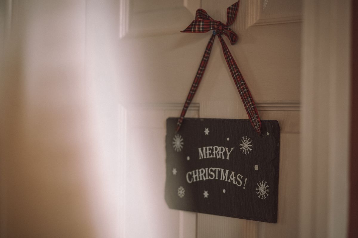 A Christmas sign with snowflakes on a door, adorned with a plaid ribbon. Stock Photo.