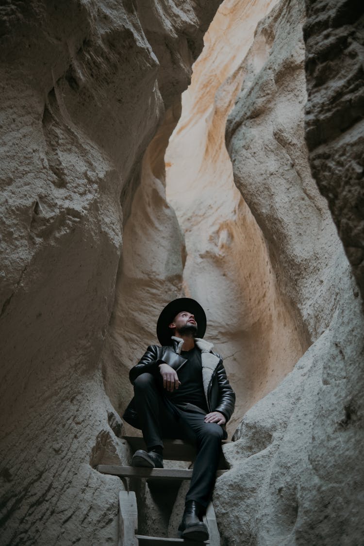 Man In Hat Sitting On Stairs In Canyon