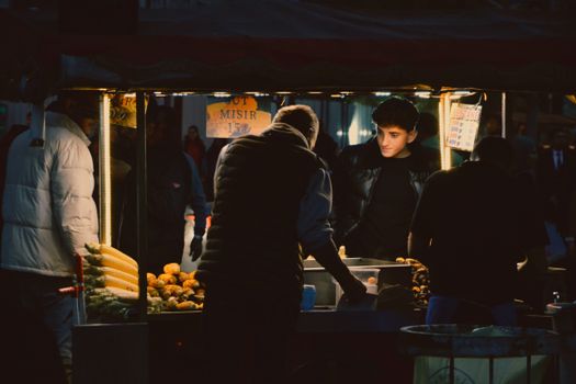 A bustling night market scene with a vendor selling street food to customers.