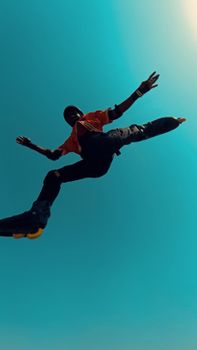 A skater performs a high jump in clear blue sky, showcasing dynamic movement and youthful energy.