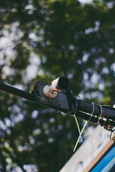 Close-up of a surveillance camera mounted outdoors on a metal pole amidst trees in São Paulo.