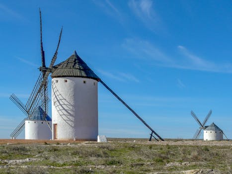 Scenic view of iconic white windmills in Campo de Criptana, Spain under a clear blue sky.