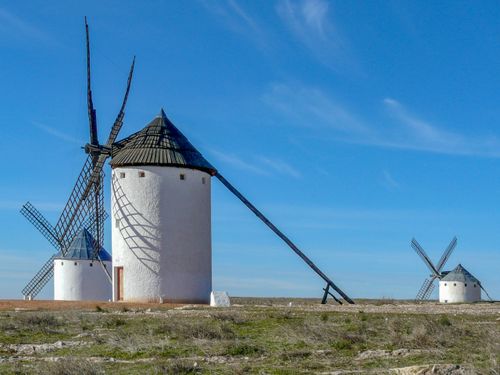 Free Scenic view of iconic white windmills in Campo de Criptana, Spain under a clear blue sky. Stock Photo
