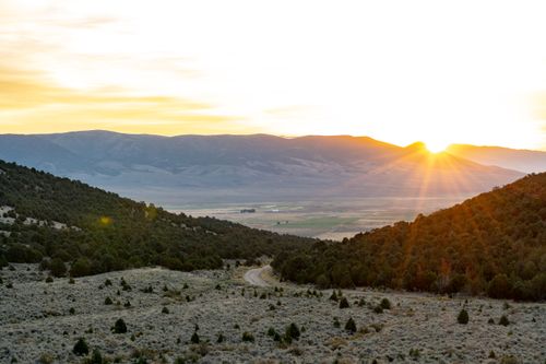 Free Captivating view of a sunset over mountains and a meandering road through a tranquil landscape. Stock Photo