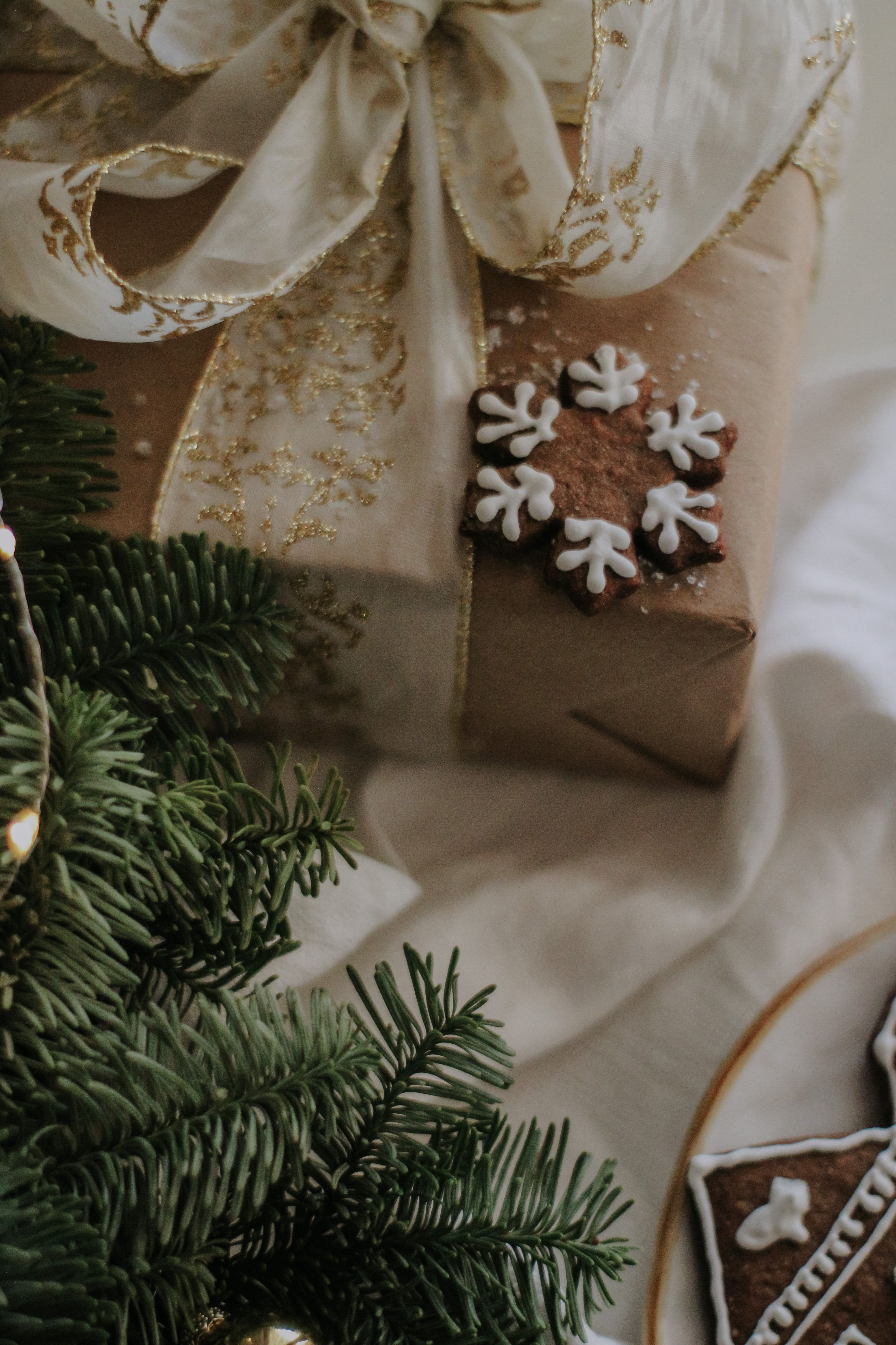 Free A beautifully wrapped Christmas gift with a gingerbread cookie and evergreen branches, creating a cozy holiday atmosphere. Stock Photo