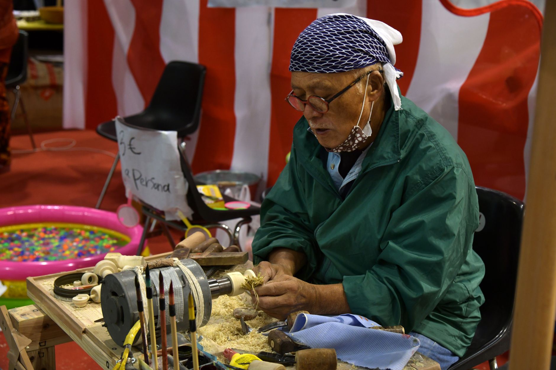 A craftsman expertly carves wood using traditional methods at a Padova event.
