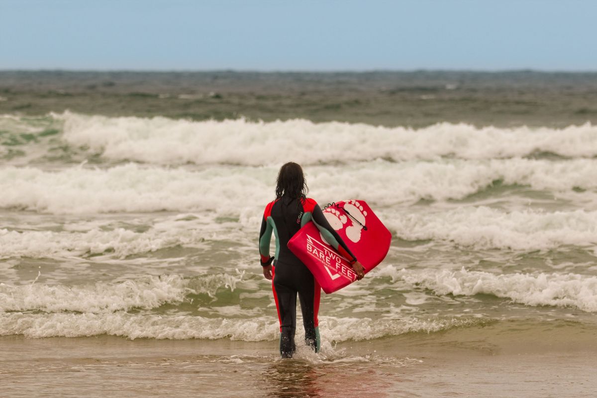 Bodyboarder holding a red board at the shoreline