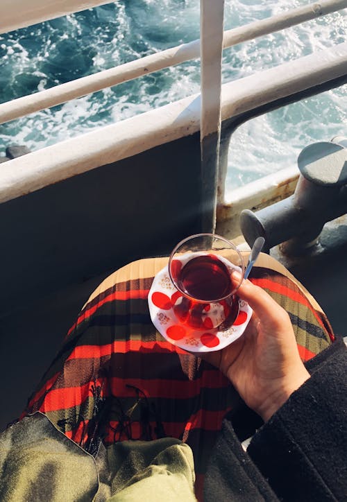 Hand of Sailing Person Holding Plate with Turkish Tea