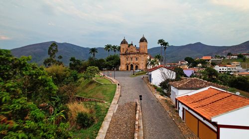 Free Aerial view of a historic church in Mariana, Brazil, set against lush greenery and mountain scenery. Stock Photo