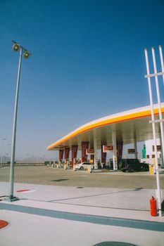 Shell gas station with vehicles under a clear blue sky in Muscat, Oman.