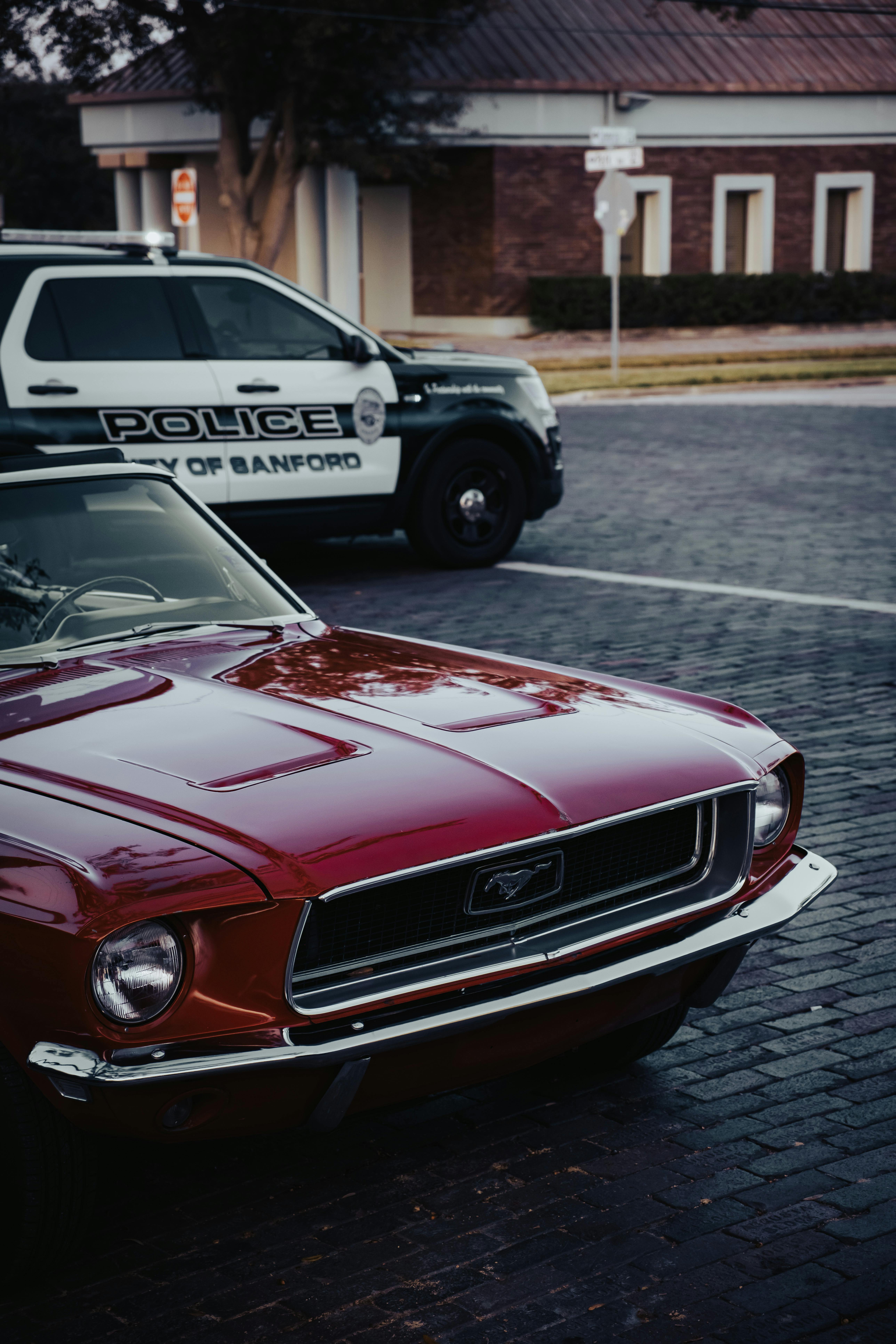 a police car is parked next to a red mustang