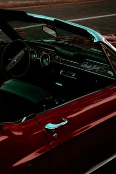 Red vintage convertible car's interior, showcasing steering wheel and dashboard features.